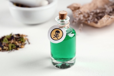 Photo of Glass bottle of poison with warning sign on light background