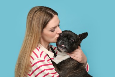 Photo of Woman hugging cute French Bulldog on light blue background