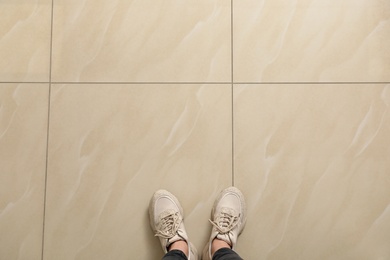 Photo of Woman standing on ceramic floor, top view. Space for text