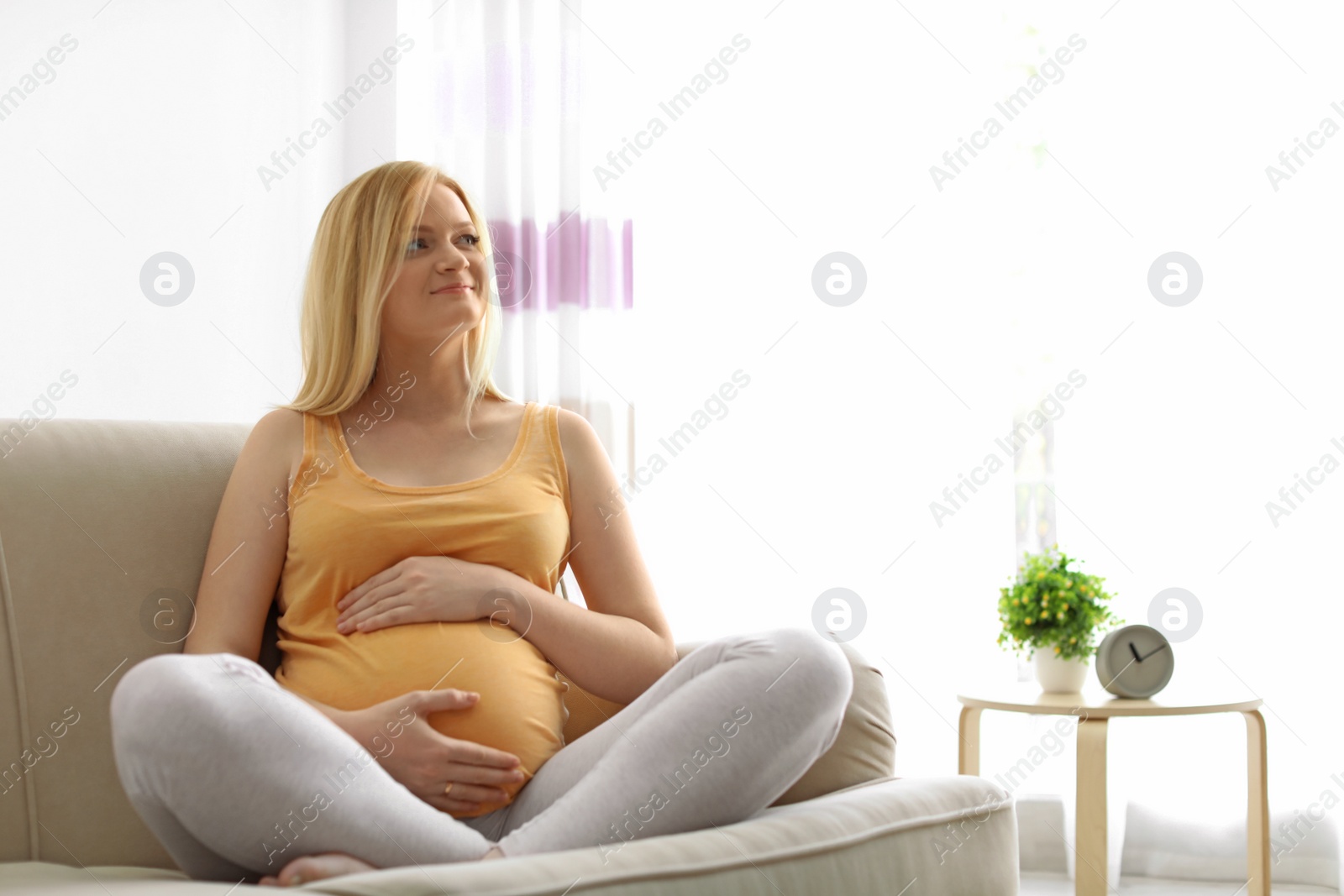 Photo of Beautiful pregnant woman sitting on sofa at home