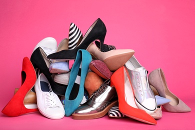 Heap of different shoes on color background