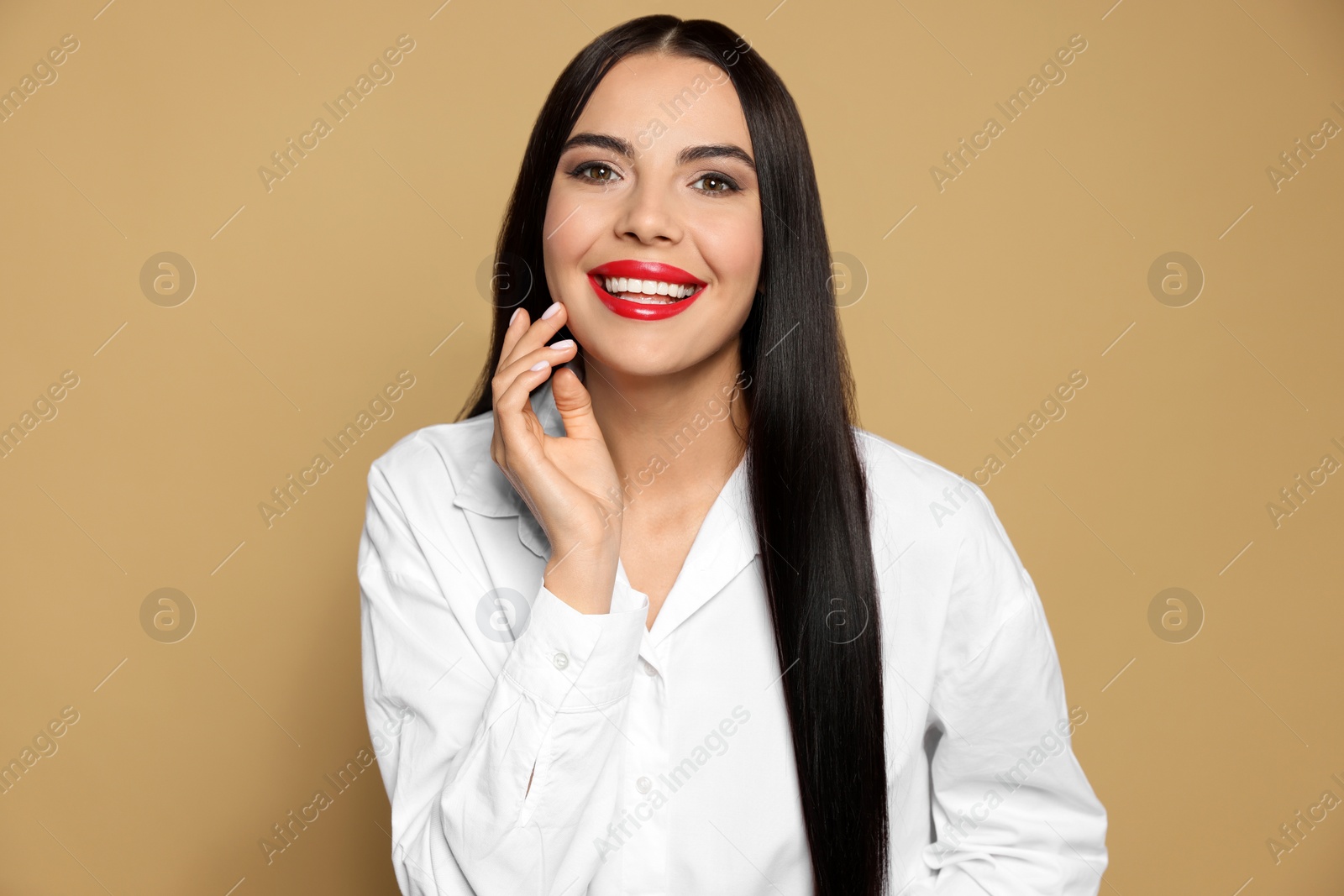 Photo of Portrait of young woman wearing beautiful red lipstick on beige background