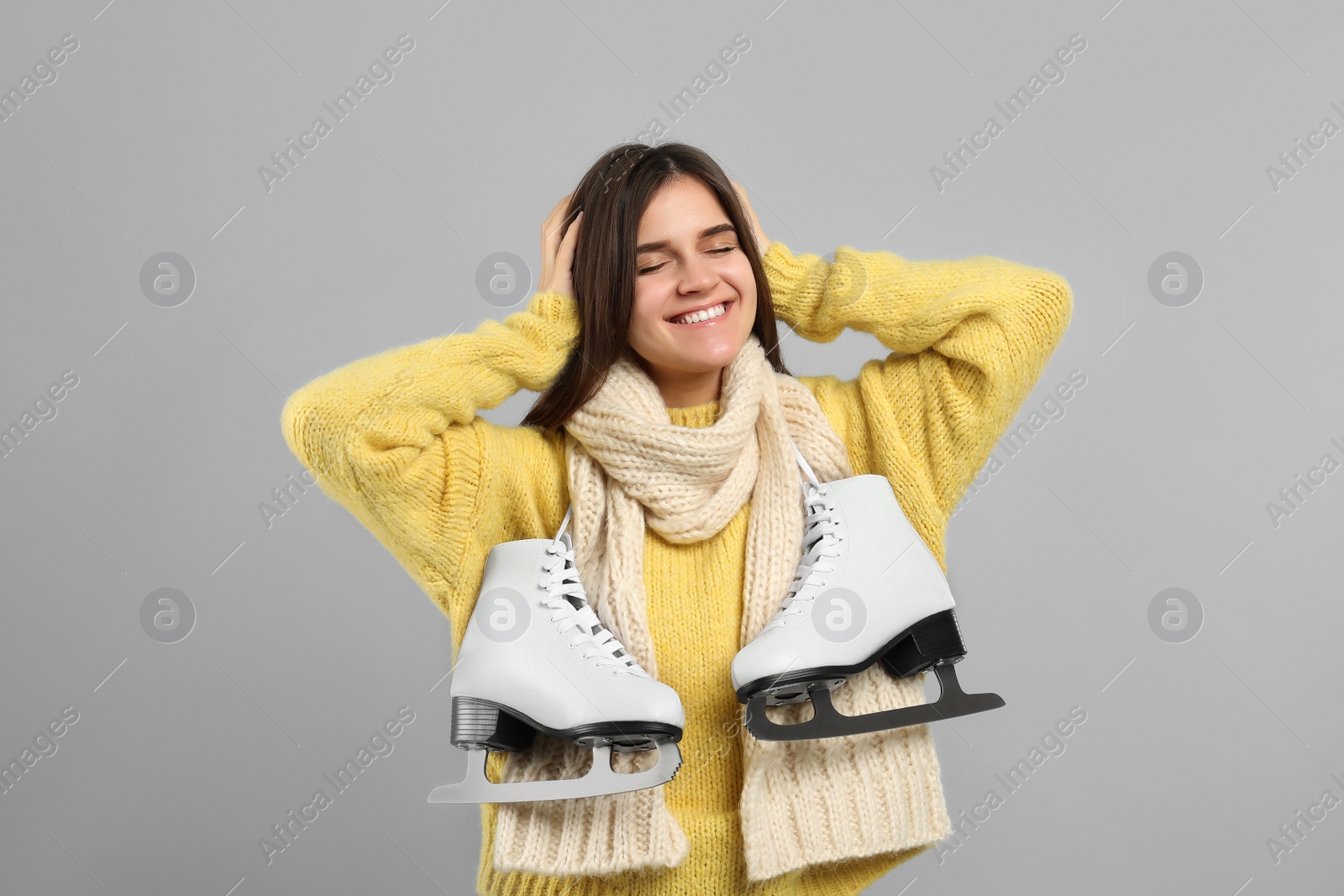 Photo of Happy woman with ice skates on grey background