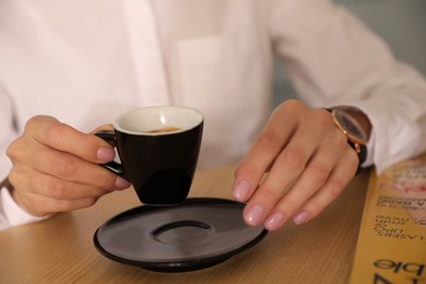 Photo of Woman with cup of coffee and magazine at cafe in morning, closeup