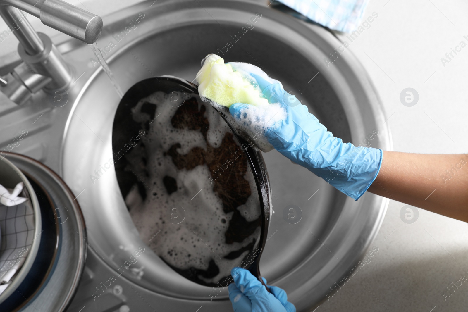 Photo of Woman washing dirty frying pan in sink, above view