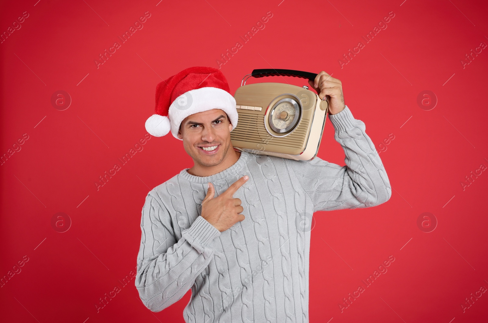 Photo of Happy man with vintage radio on red background. Christmas music