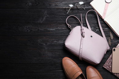 Flat lay composition with stylish shoes, woman's bag and smartphone on black wooden table. Space for text