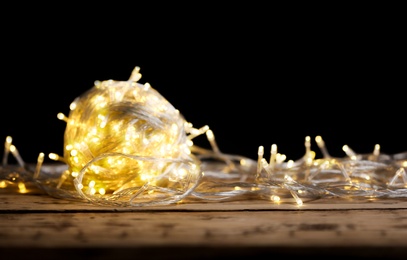 Photo of Yellow Christmas lights on wooden table against black background