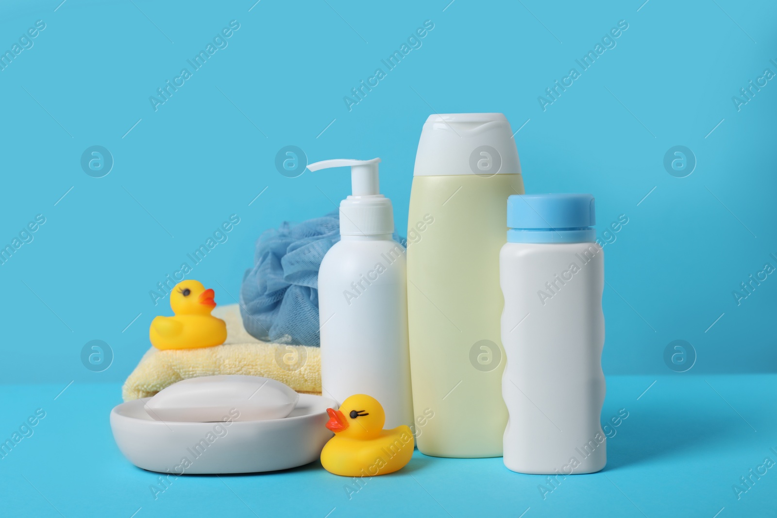 Photo of Baby cosmetic products, bath ducks, sponge and towel on light blue background