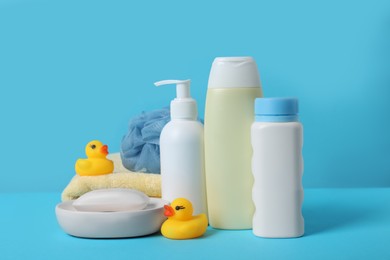 Baby cosmetic products, bath ducks, sponge and towel on light blue background