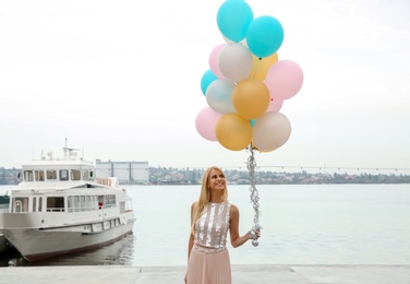 Photo of Beautiful young woman with bunch of balloons outdoors