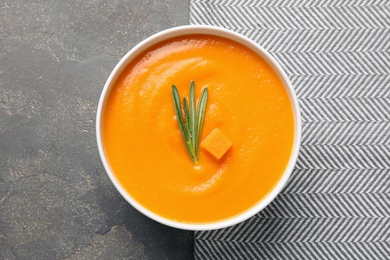 Bowl of tasty pumpkin soup on gray background, top view