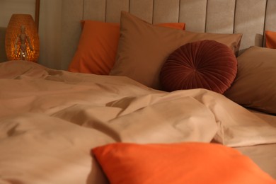 Photo of Bed with brown linen and different pillows in room