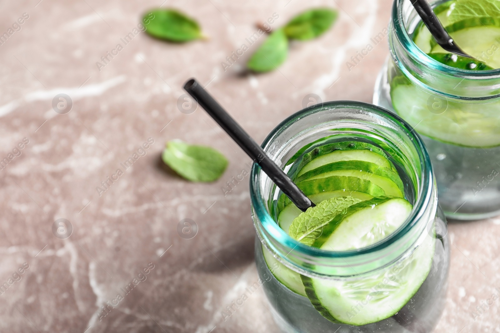 Photo of Jars with fresh cucumber water on grey background, closeup. Space for text