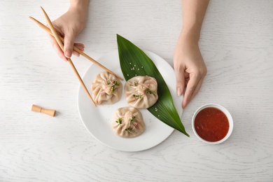 Photo of Woman eating tasty baozi dumplings at table, top view