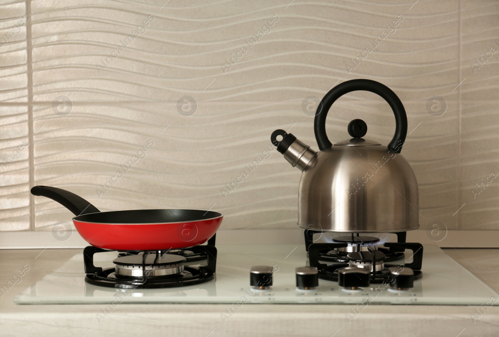 Photo of Steel kettle and frying pan on modern gas stove. Space for text