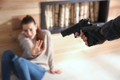 Photo of Man aiming his victim with gun indoors, closeup. Dangerous criminal