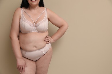 Photo of Beautiful overweight woman in underwear on beige background, closeup with space for text. Plus-size model