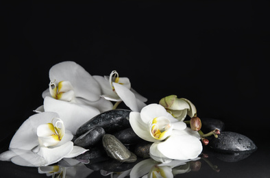 Photo of Stones and orchid flowers in water on black background. Zen lifestyle