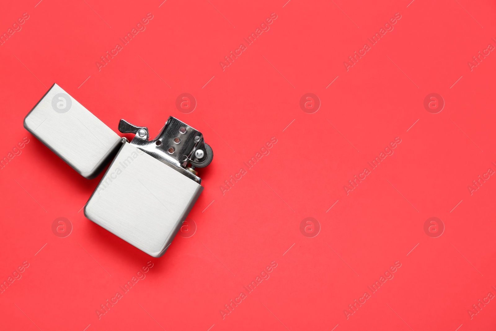 Photo of Gray metallic cigarette lighter on red background, top view. Space for text