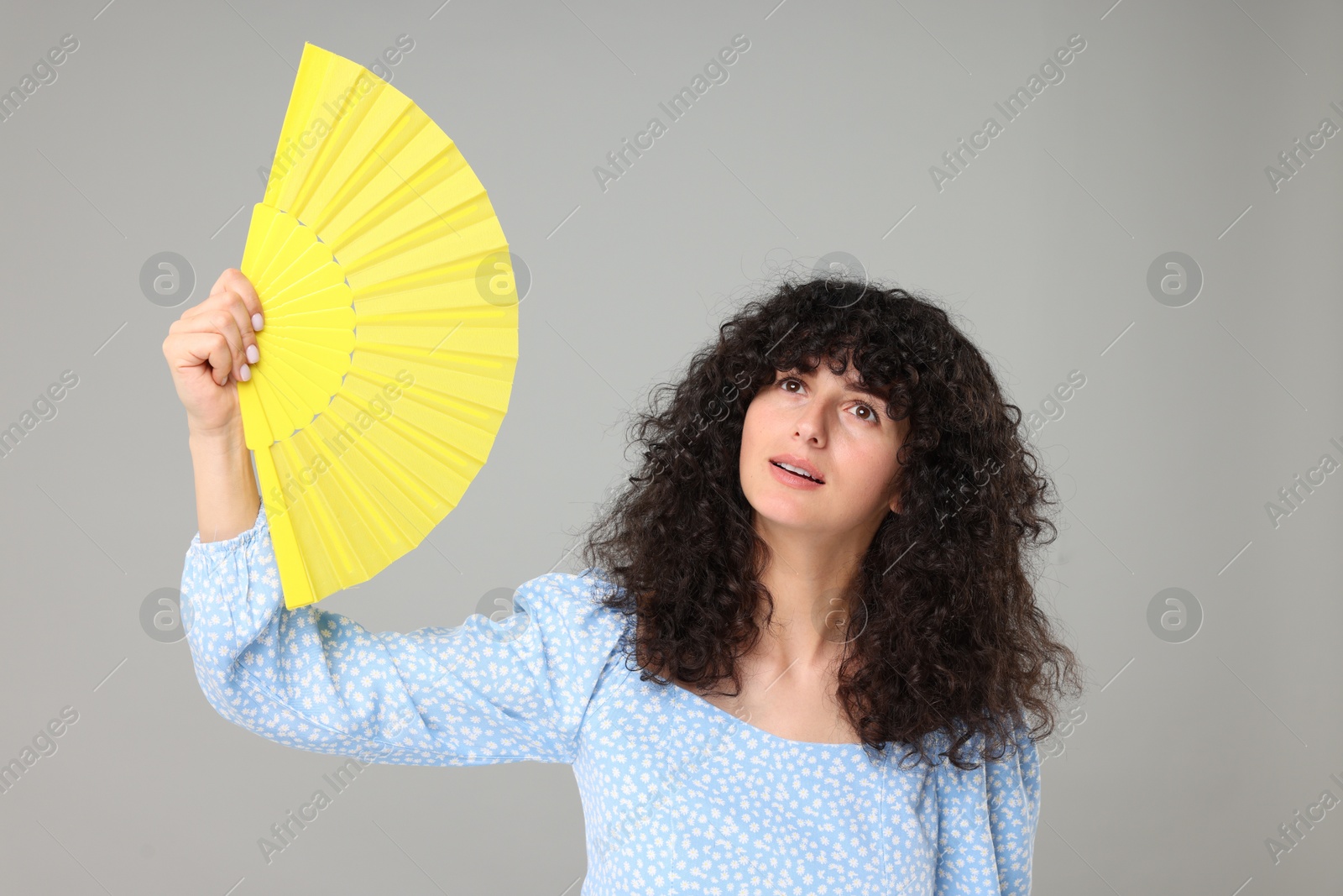 Photo of Woman with hand fan suffering from heat on light grey background