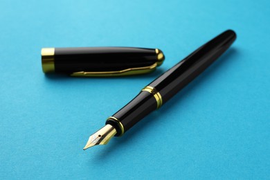 Stylish fountain pen with cap on light blue background, closeup