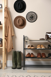 Photo of Rack with different shoes near beige wall in room