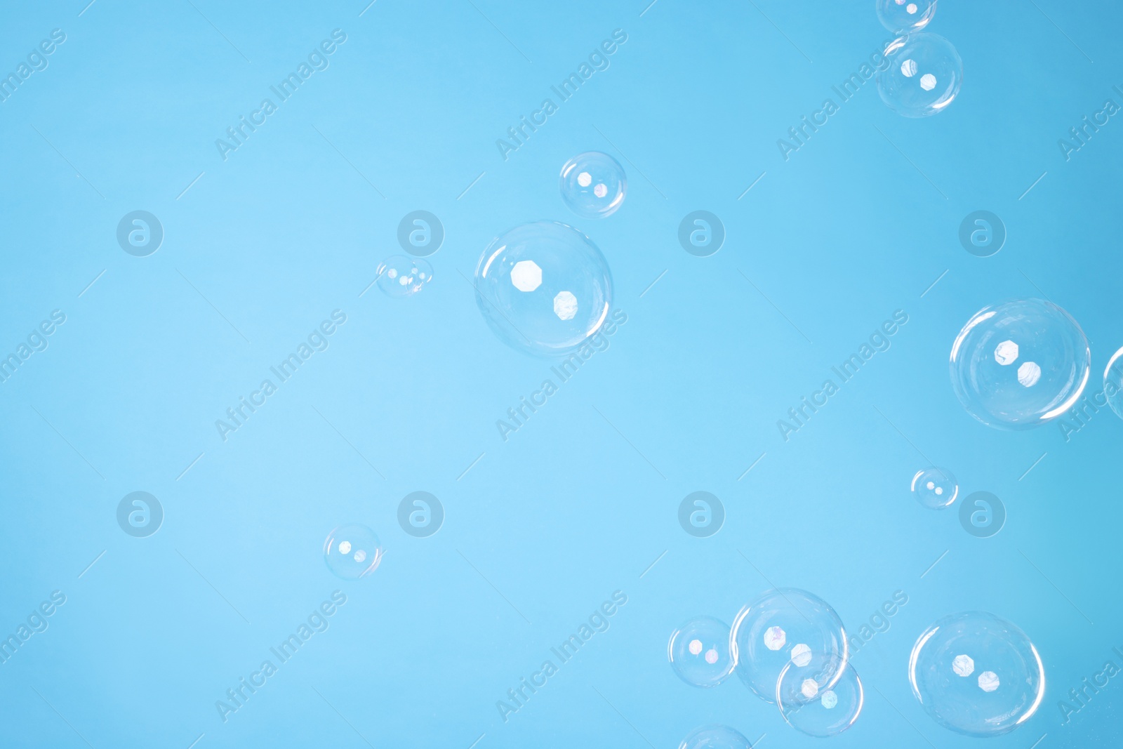 Photo of Many beautiful soap bubbles on light blue background. Space for text