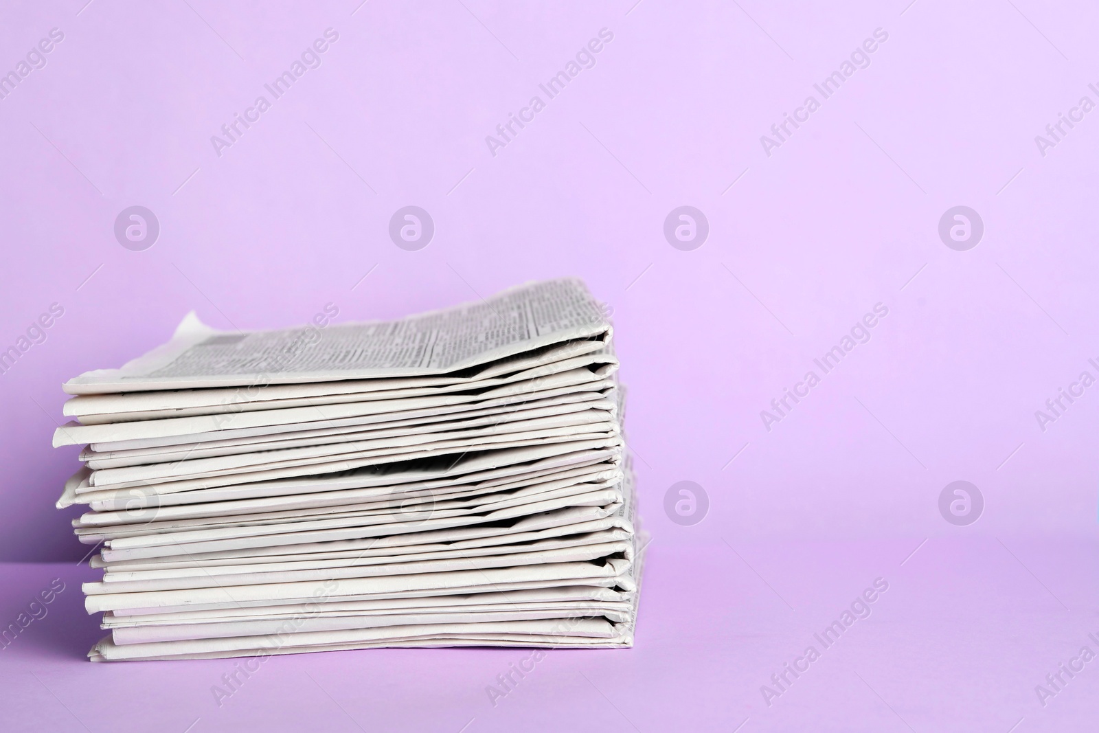 Photo of Stack of newspapers on light violet background, space for text. Journalist's work