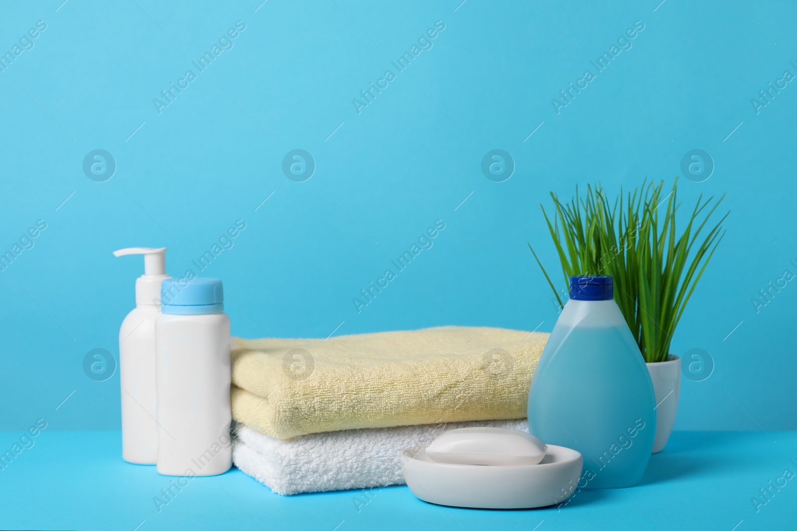 Photo of Baby cosmetic products and towels on light blue background