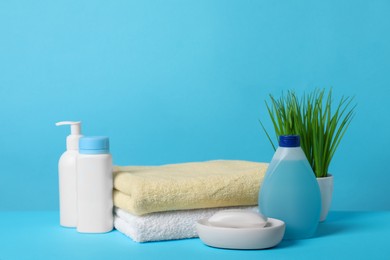 Baby cosmetic products and towels on light blue background