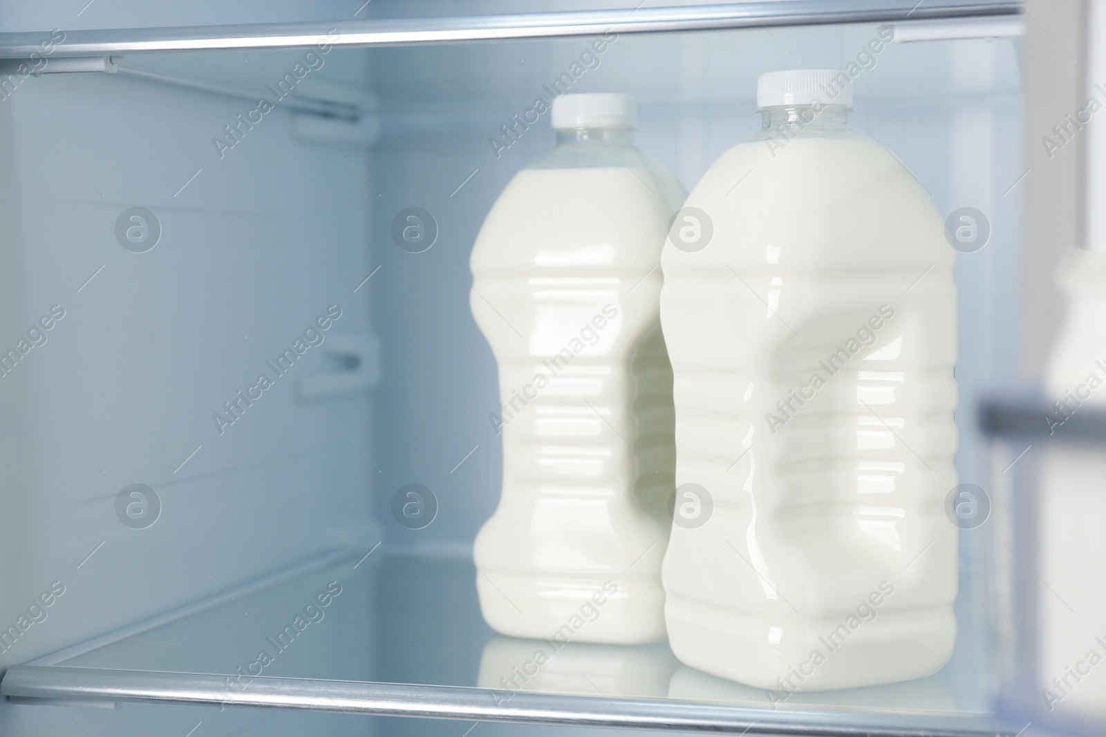 Photo of Gallons of fresh milk in refrigerator, closeup. Space for text