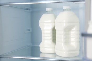 Photo of Gallons of fresh milk in refrigerator, closeup. Space for text
