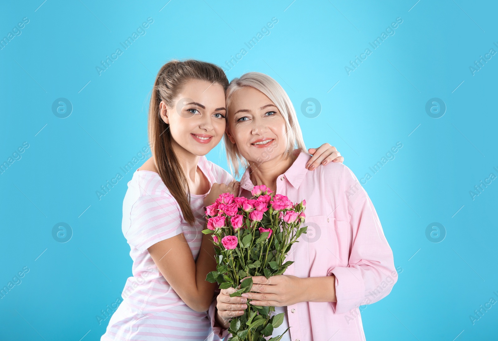 Photo of Young daughter congratulating her mature mother on color background. Happy Women's Day