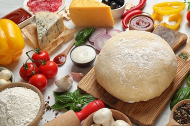 Photo of Fresh dough and ingredients for pizza on white table