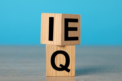 Wooden cubes with letters E, I and Q on table