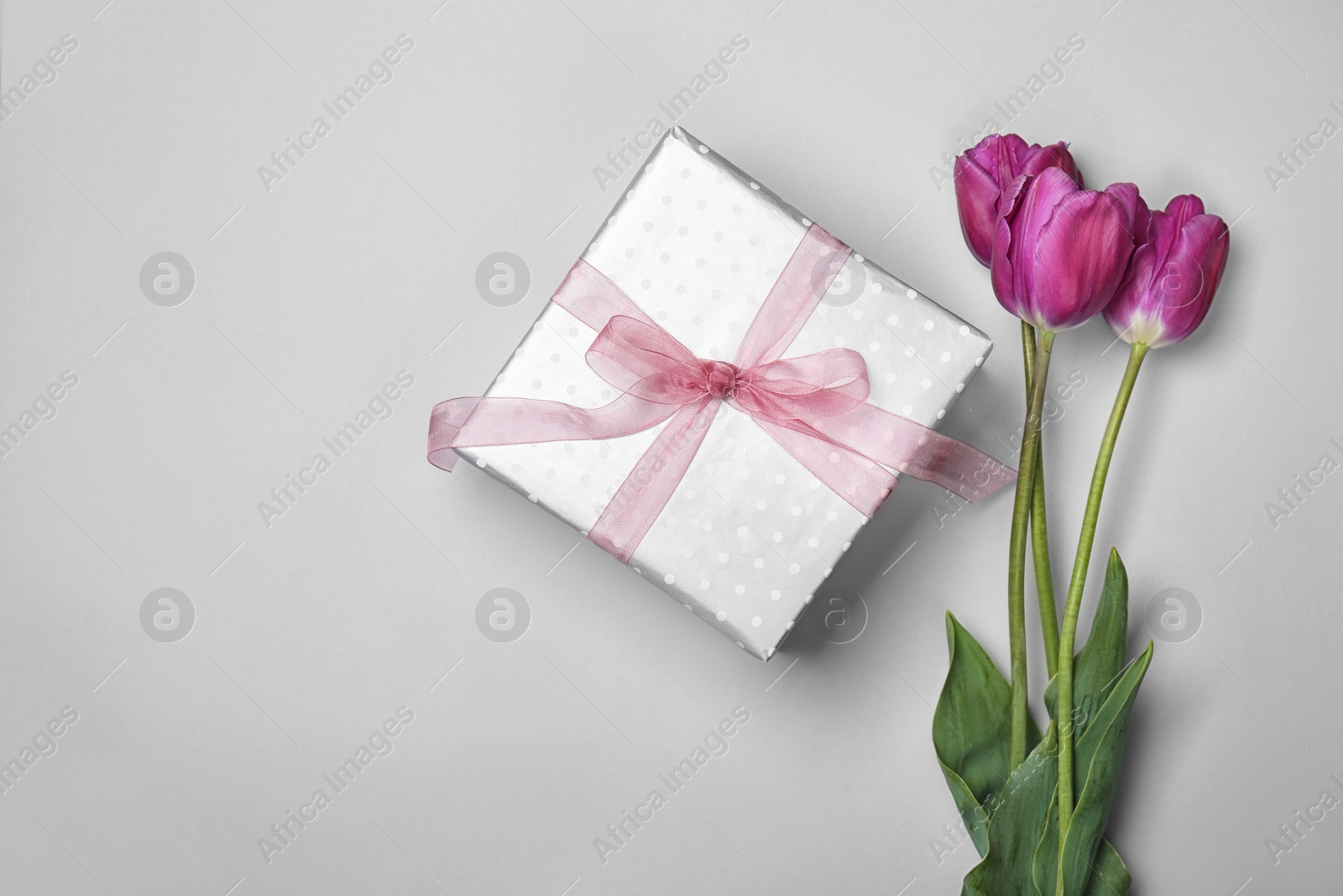 Photo of Flat lay composition with elegant gift box and tulips for Mother's Day on light background