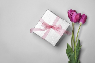 Photo of Flat lay composition with elegant gift box and tulips for Mother's Day on light background