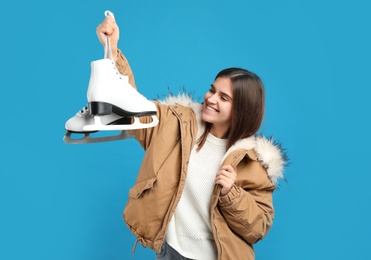 Happy woman with ice skates on light blue background