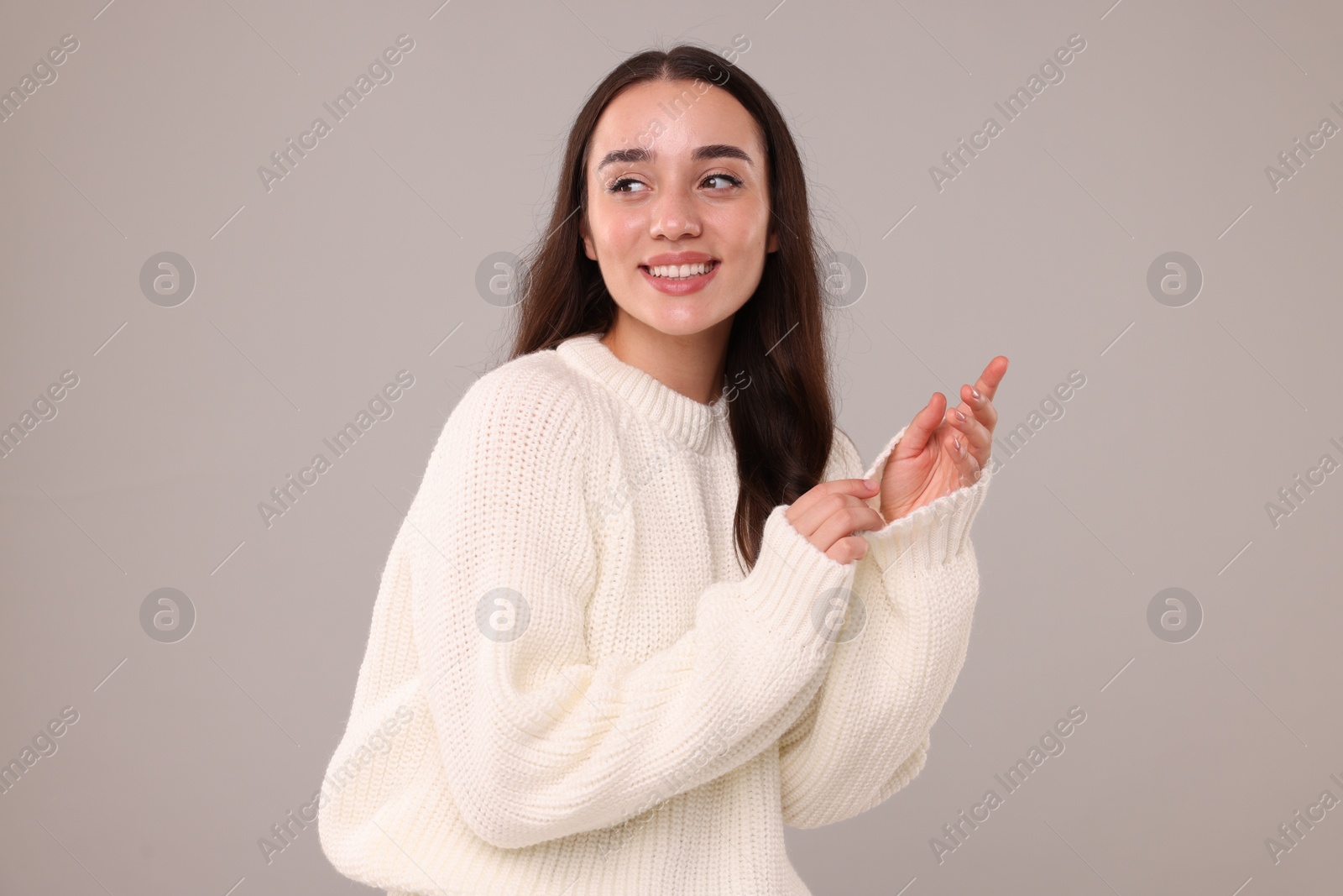 Photo of Beautiful young woman in stylish warm sweater on grey background