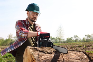 Photo of Man sawing wooden log on sunny day