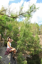 Photo of Young woman on rocky mountain in forest. Camping season