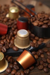 Coffee capsules and beans on wooden table, closeup