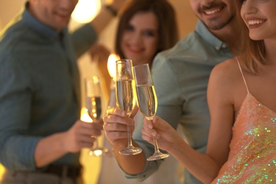 Friends clinking glasses with champagne at party indoors