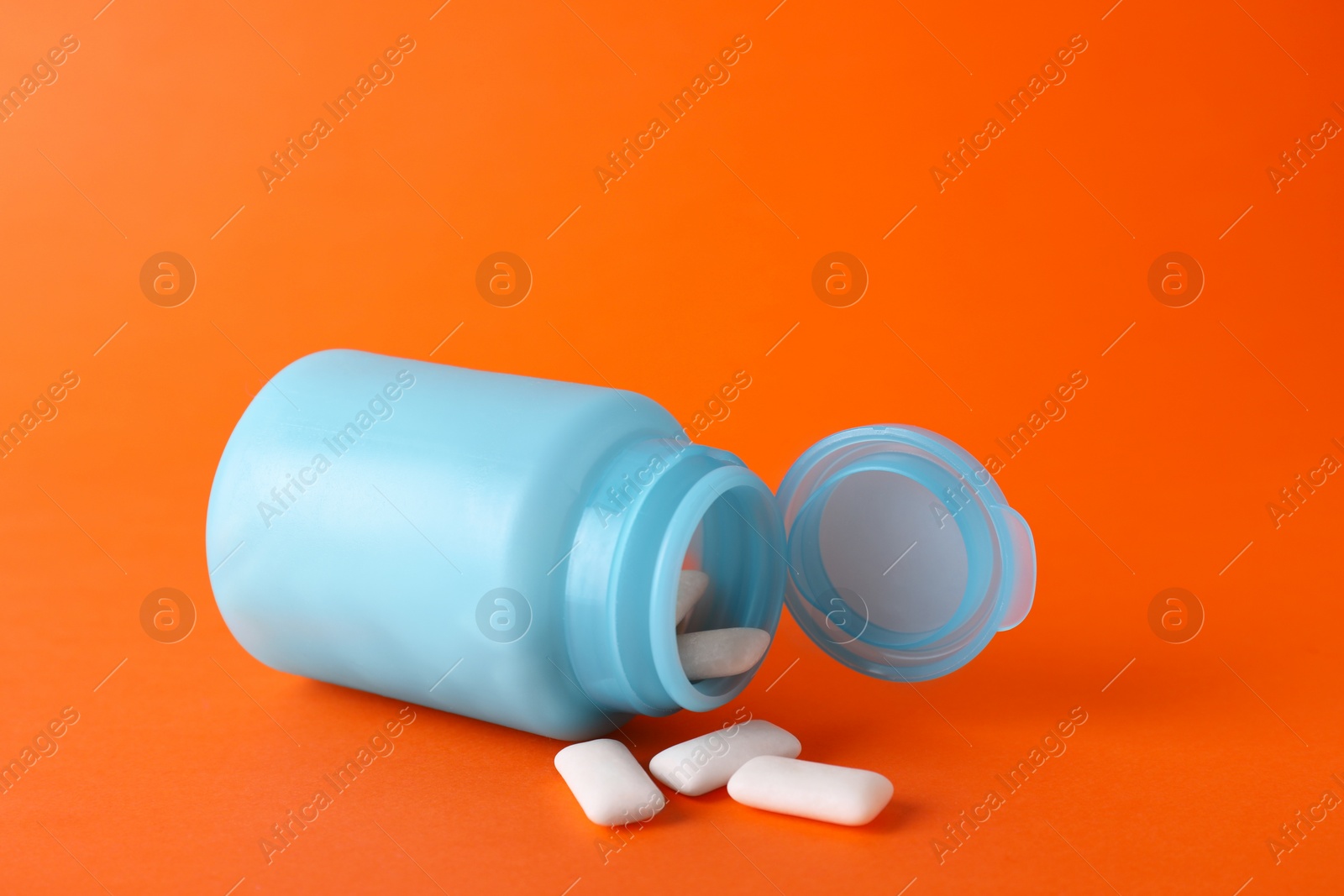 Photo of Jar with chewing gums on orange background