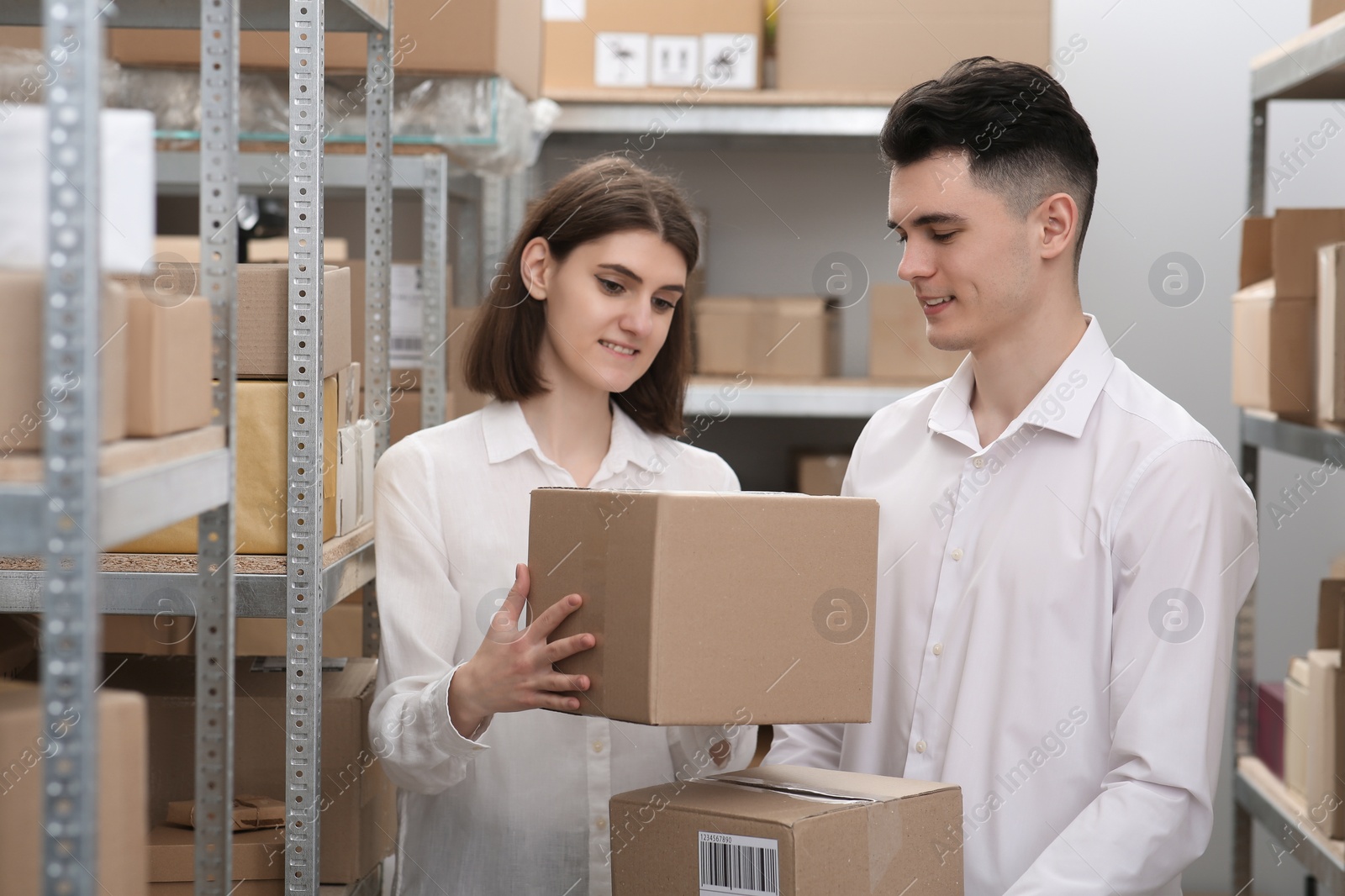 Photo of Post office workers with parcels near rack indoors