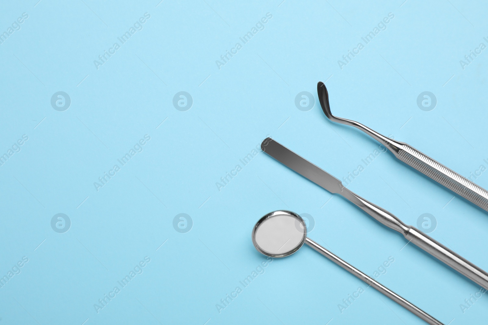 Photo of Set of different dentist's tools on light blue background, flat lay. Space for text