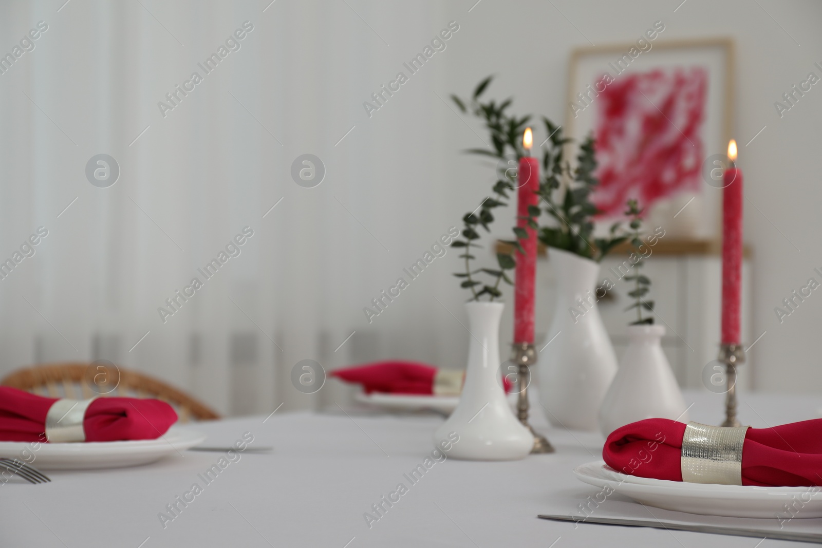 Photo of Beautiful table setting with green branches in vases and burning candles indoors. Stylish dining room