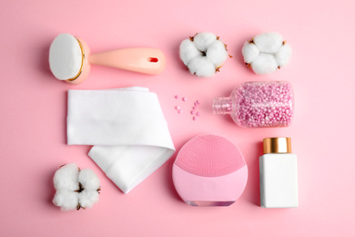 Flat lay composition with face cleansing brushes on pink background. Cosmetic tools