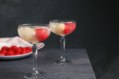 Photo of Glasses with tasty melon and watermelon ball drink on dark table. Space for text